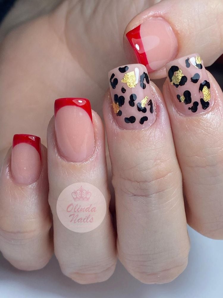 Mão de pele clara com unhas quadradas curtas, com francesinhas vermelhas e animal print onça