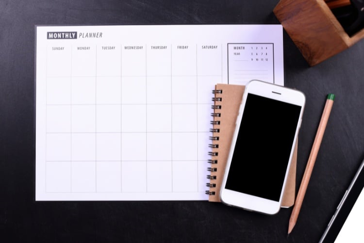 Foto de planner em branco ao lado de agenda marrom e celular 