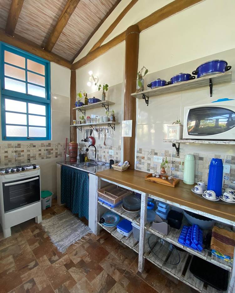 Decoração de cozinha estilo rural com prateleiras e utensílios de cozinha pendurados, tudo na cor azul