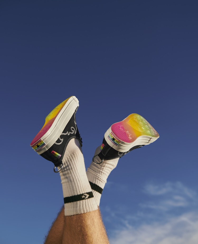 Foto de pessoa com os pés para cima, usando o tênis Converse Pride 2024 Chuck 70 Ox