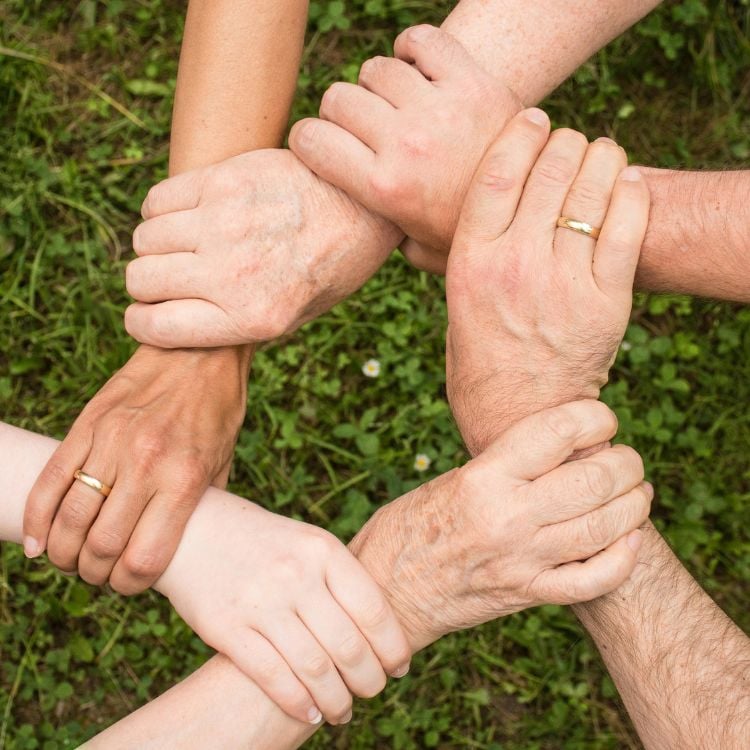 Foto de mãos de 6 pessoas interligadas, simbolizando o que significa trabalhar com espiritualidade