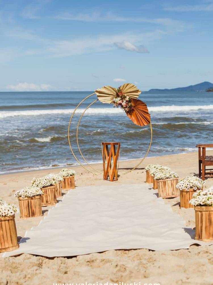 Casamento na praia com arco de flor de metal e pouca decoração