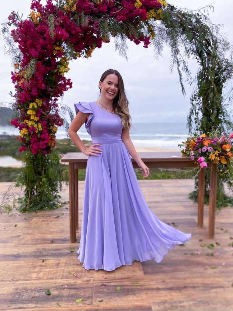 Mulher de pele clara usando vestido lilás de um ombro só em casamento na praia