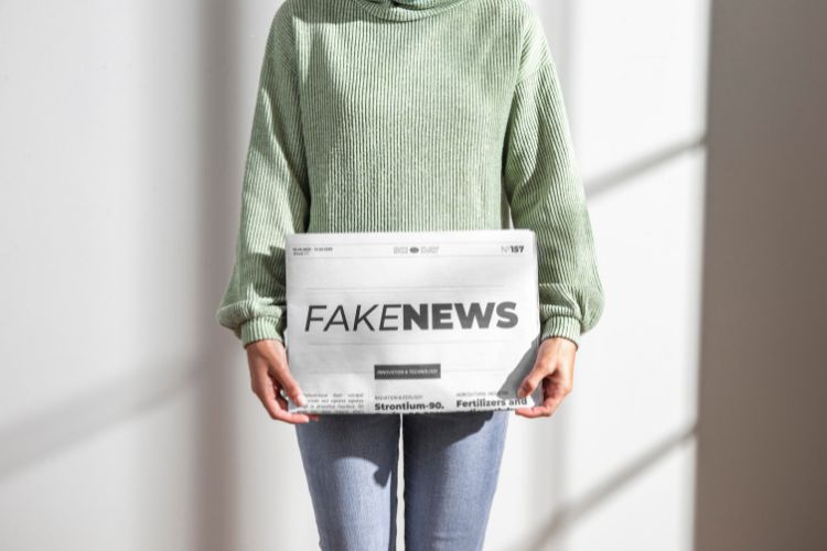 Mulher segurando jornal com manchete FakeNews