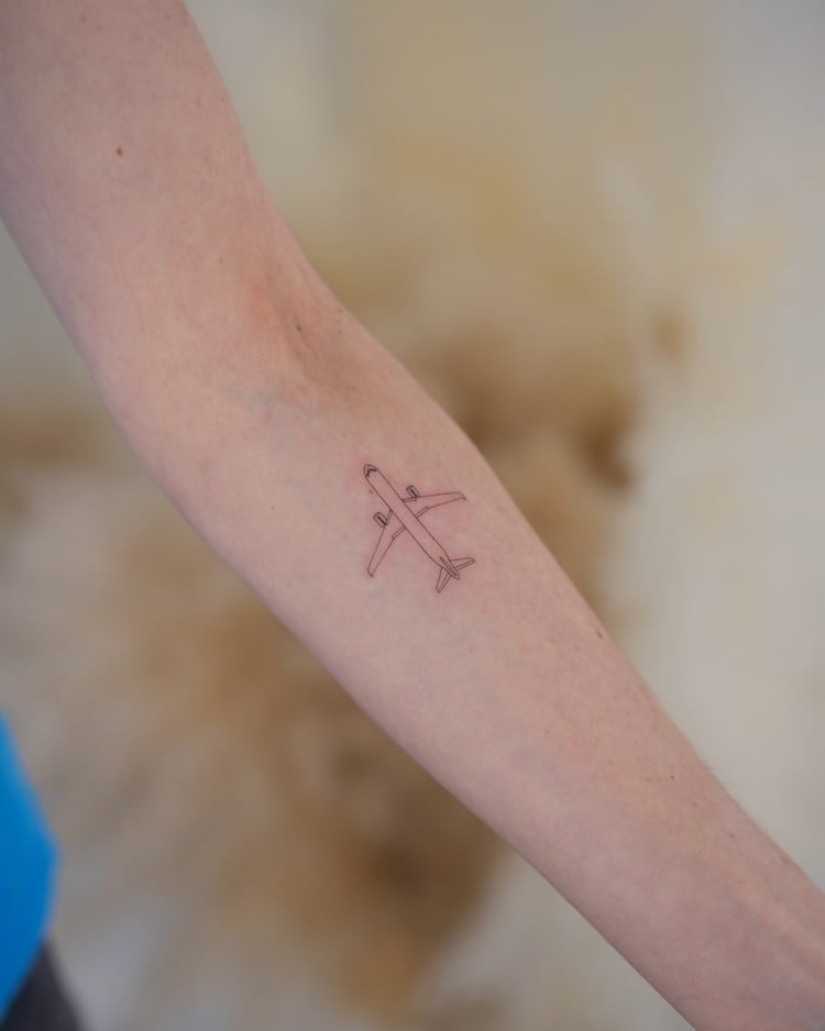Tatuagem de traços finos de avião em braço