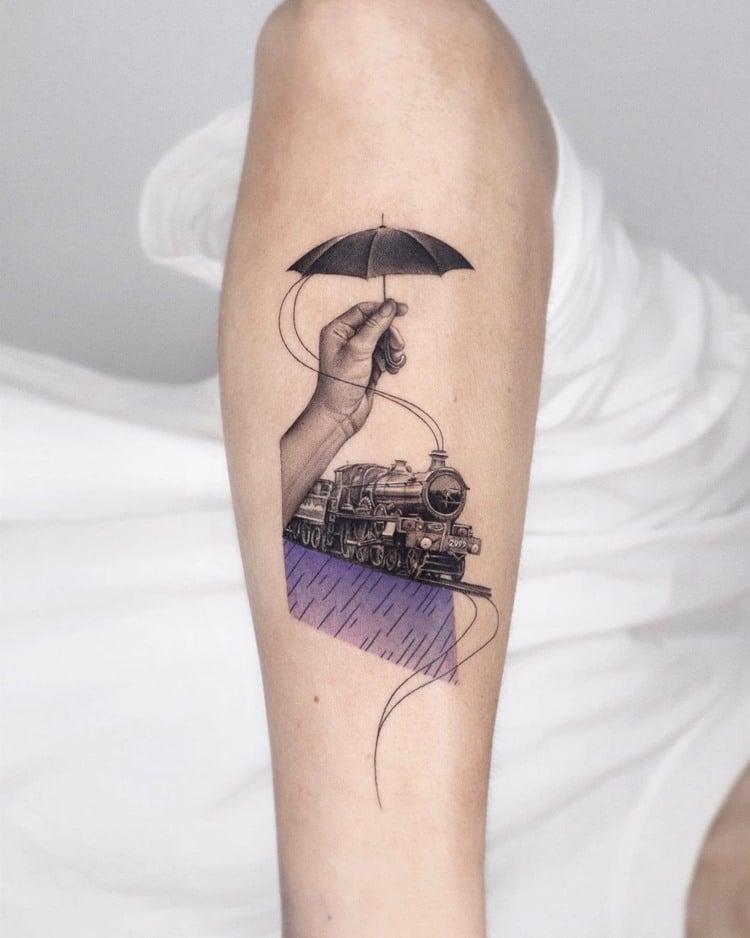 Tatuagem de trem com mão segurando um mini guarda-chuva