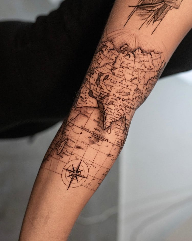 Tatuagem de mapa em globo com estrela de bússola em braço de homem