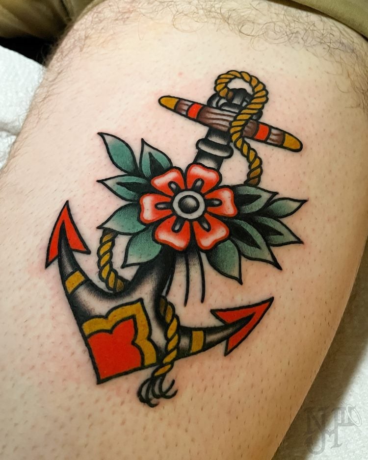 tatuagem de âncora preta com flor e corda em braço estilo old school