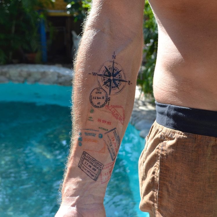 tatuagem de viagem masculina de bússola e carimbos de países diferentes de passaportes