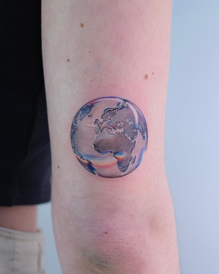 Tatuagem de mundo numa espécie de bolha de sabão em braço