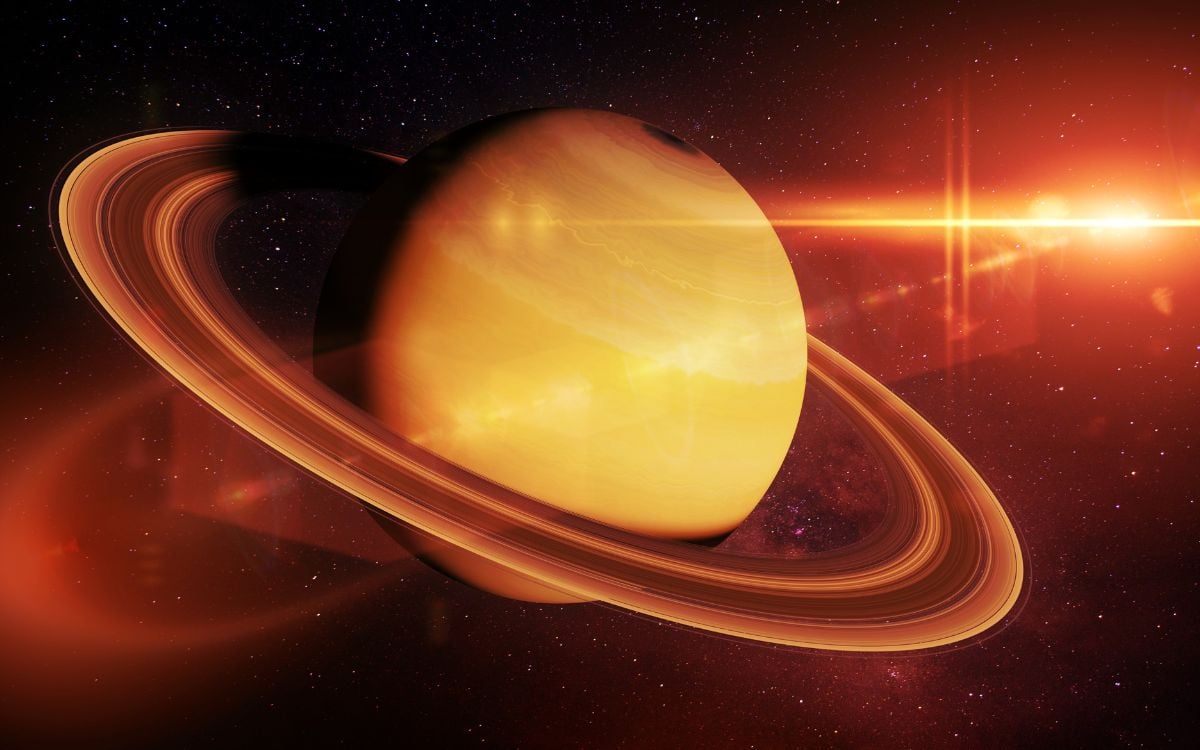 Foto de planeta Saturno em movimento retrógrado, com luz vermelha vindo da direita