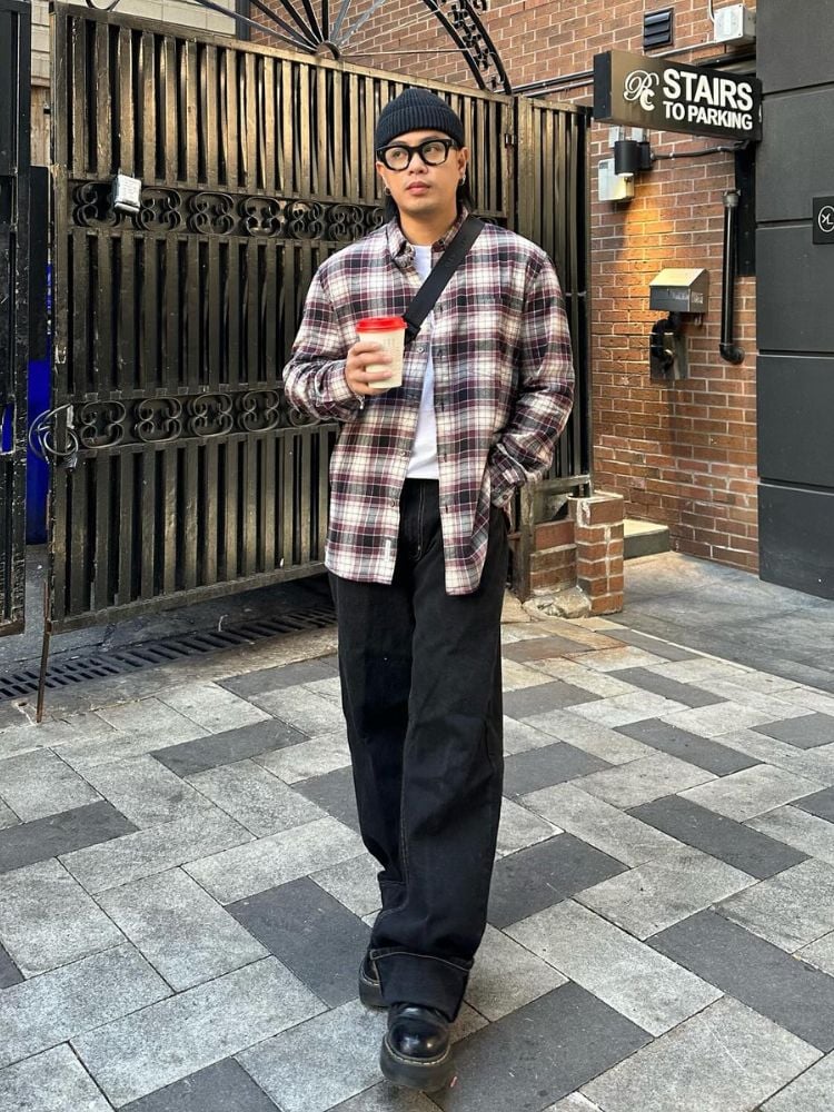 Homem usando camiseta branca, camisa xadrez e calça jeans preta