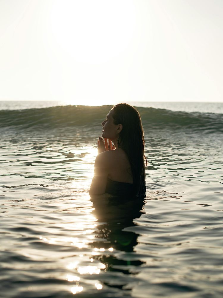 Foto de mulher fazendo cura do Sagrado Feminino por meio da conexão com a natureza em um mergulho no mar