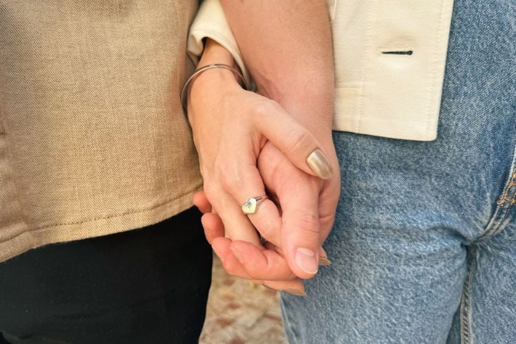 Foto de casal de namorados de mãos dadas. Ela usa anel Bae da marca Cuff