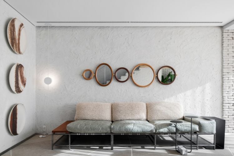 Foto de sala de estar com sofá de crochê e couro e com espelhos na parede texturizada