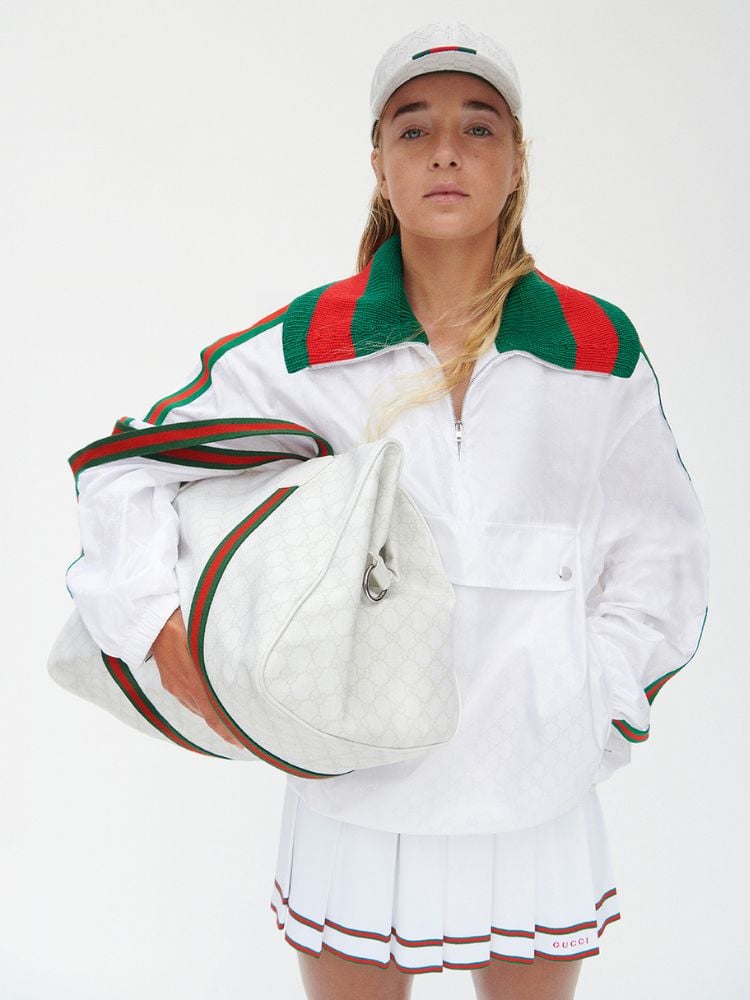 Mulher usando look da coleção Gucci Tennis: boné, jaqueta, saia e bolsa