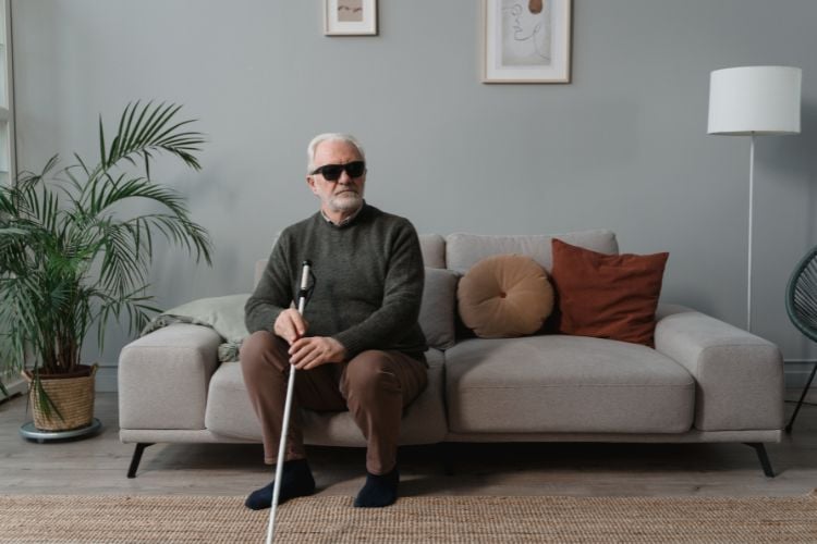 Homem idoso com deficiência visual sentado em um sofá macio