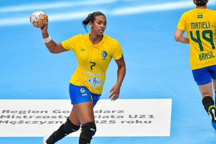 Atleta de pele morena, camisa 7 da seleção brasileira feminina de handebol, segurando a bola em quadra