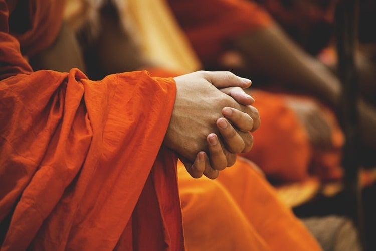 Mãos unidas de um monge da religião budista 