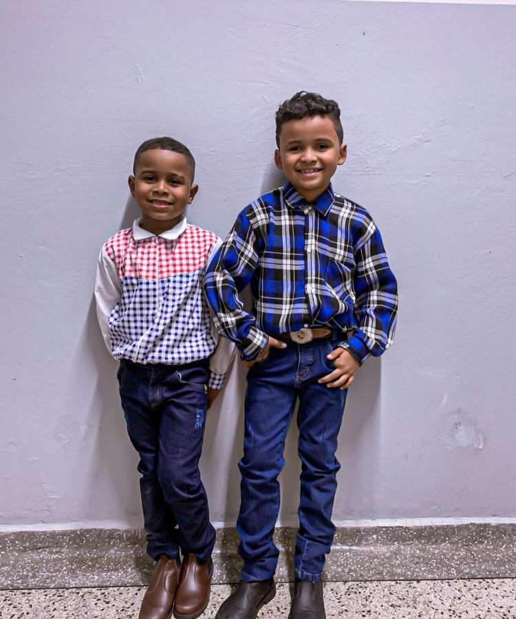 Dois meninos usando camisa xadrez, calça jeans e sapatão para festa junina.