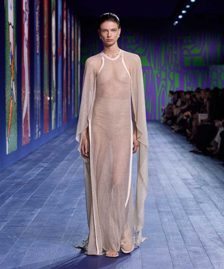 Modelo usa vestido longo, transparente e brilhante, com mangas esvoaçantes e decote halter em desfile da Dior na Semana de Alta Costura de Paris inverno 2024