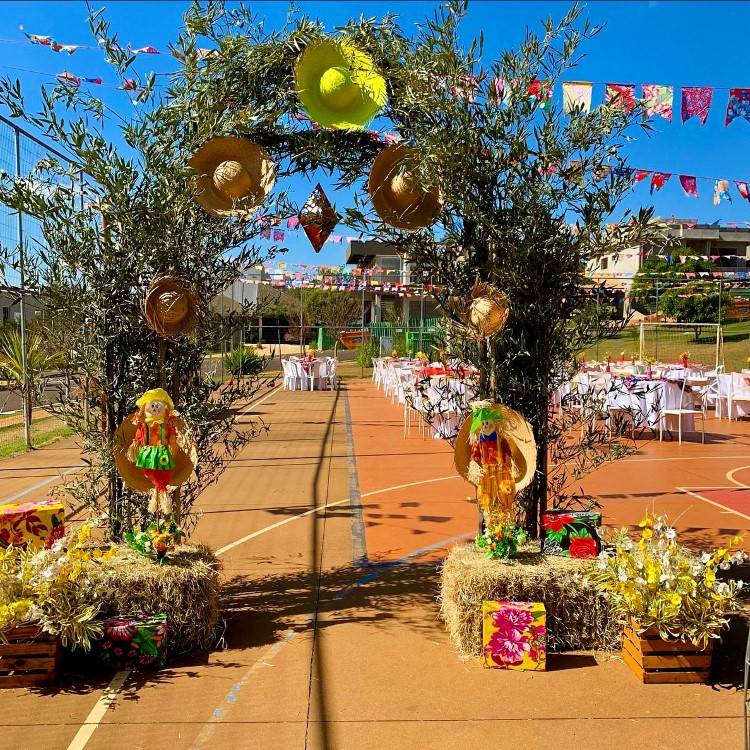 Portal de festa junina feito com falhos de árvore e decorado com chapéus de palha