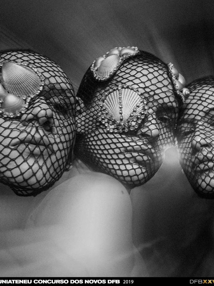 Foto em preto e branco de três mulheres com meia arrastão no rosto e conchas