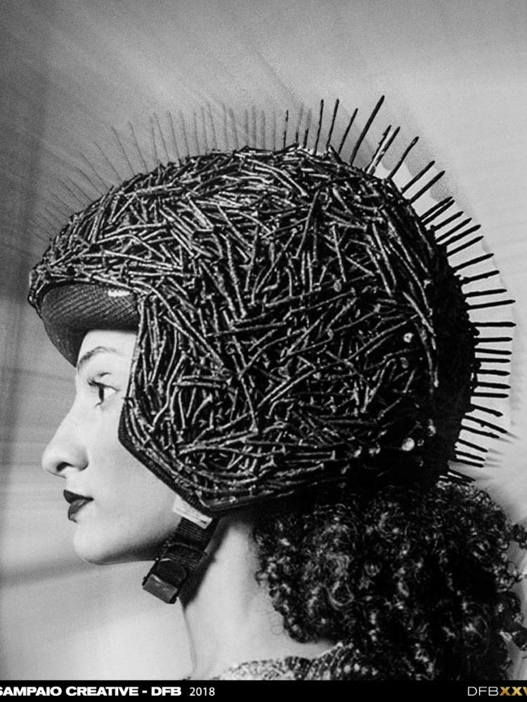 Foto em preto e branco de mulher com capacete com hastes de ferro e pregos