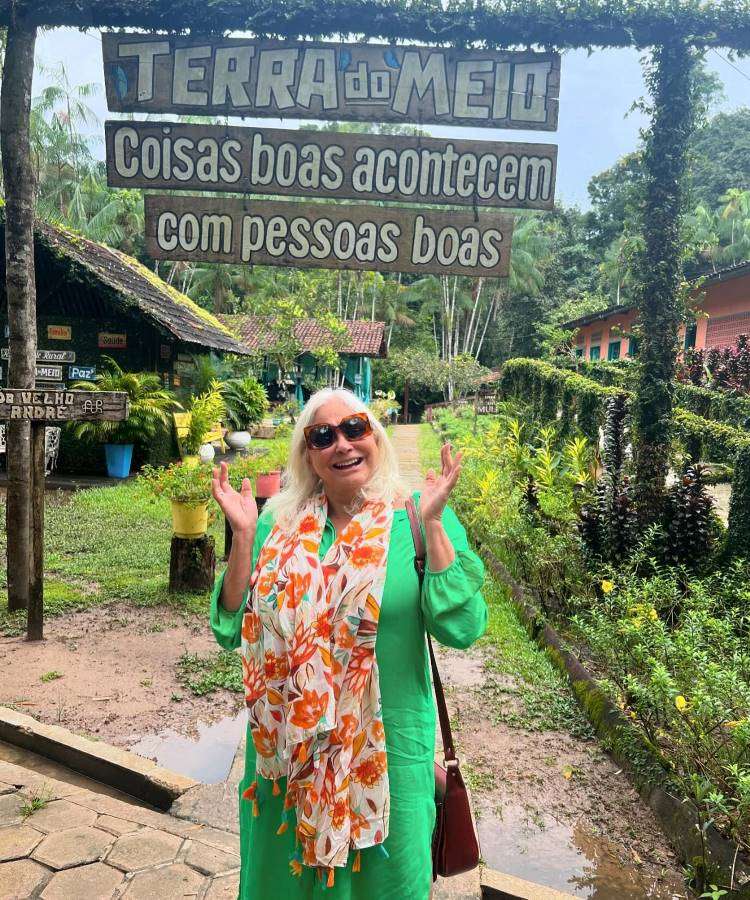 Cantora Fafá de Belém usando vestido verde com cachecol, óculos de sol em um lugar possivelmente uma pousada