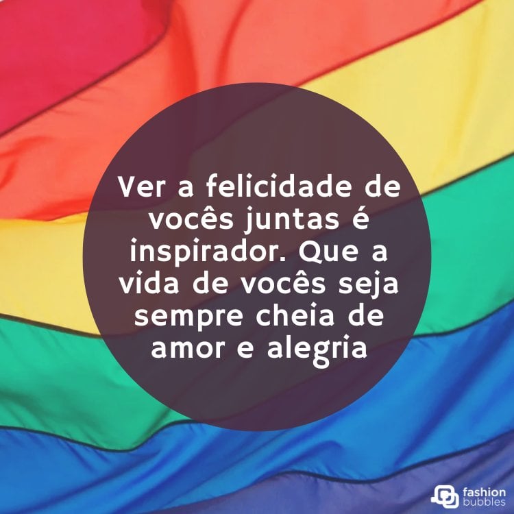 Foto de bandeira LGBT voando e círculo roxo com frase "Ver a felicidade de vocês juntas é inspirador. Que a vida de vocês seja sempre cheia de amor e alegria."
