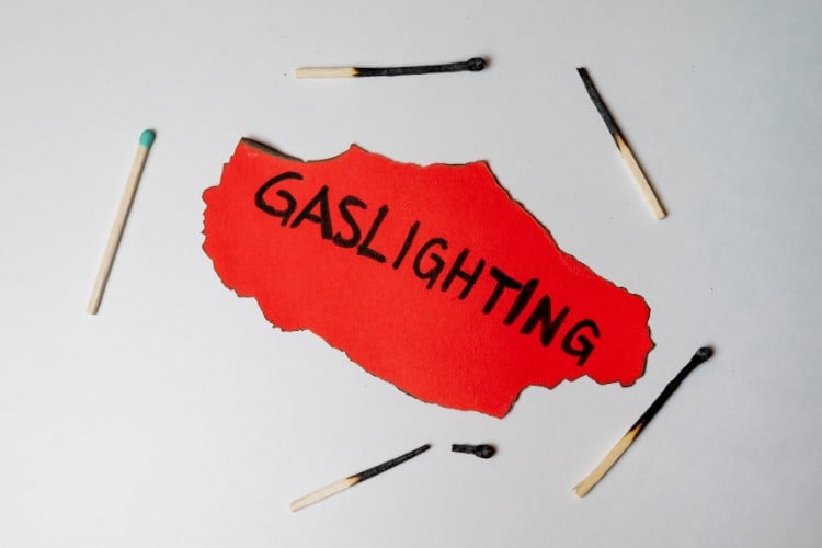 Foto de fósforos apagados com papel vermelho rasgado escrito "gaslighting"