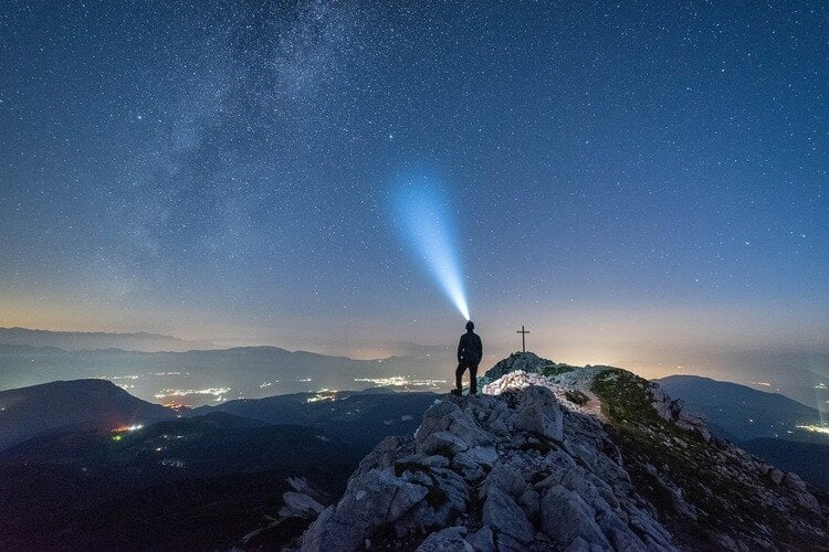 Homem em um ponto alto da terra avistando uma luz no céu