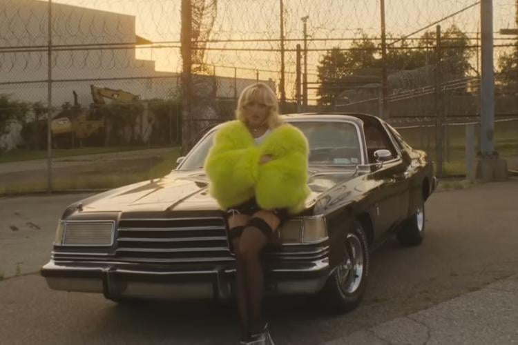Sabrina Carpenter estrela em seu videoclipe "Please Please Please" usando casaco felpudo verde limão