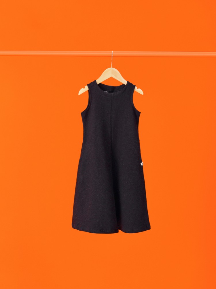 Foto de vestido slim preto pendurado na frente de fundo laranja