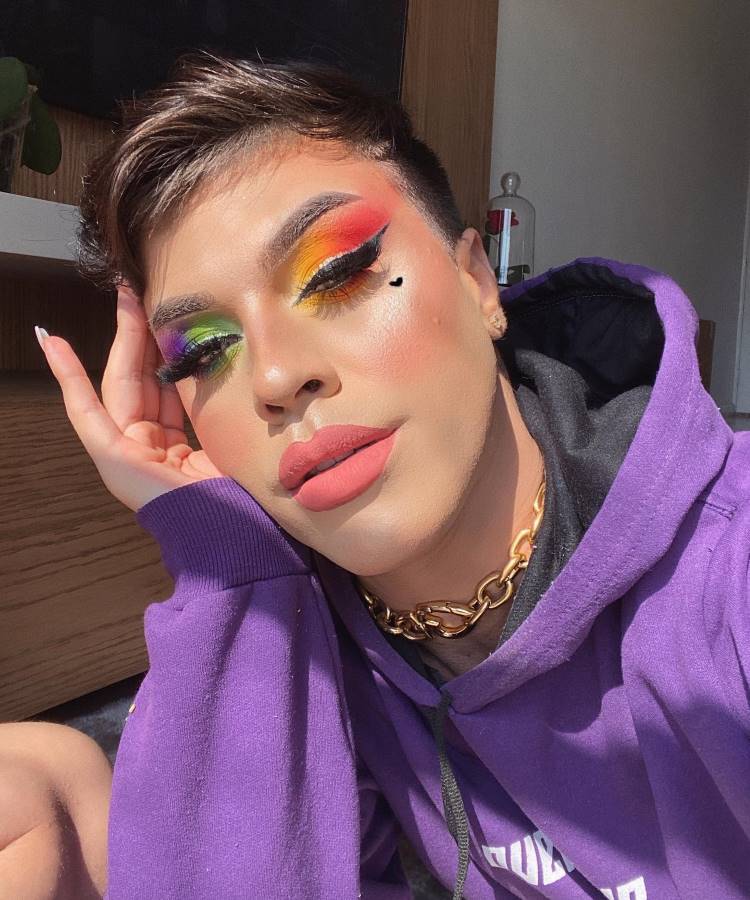 Maquiador Luccas LGBT, com moletom roxo, e make colorida nos olhos