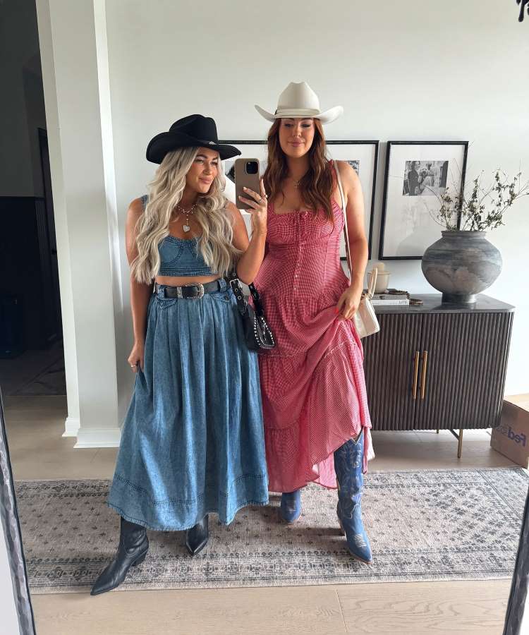Duas mulheres em foto no espelho de casa. Ambas usam chapéu cowboy. Uma está com look jeans composto por top e saia longa, e a outra de vestido vermelho xadrez. Ambas estão com botas western.