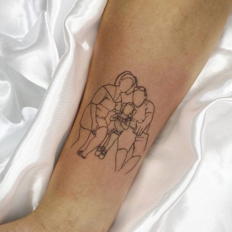 Foto de braço de pessoa de pele clara com tatuagem de contorno de foto, com dois adultos e uma criança