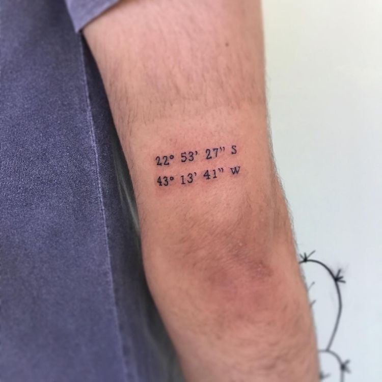 Braço de homem tatuado com coordenadas