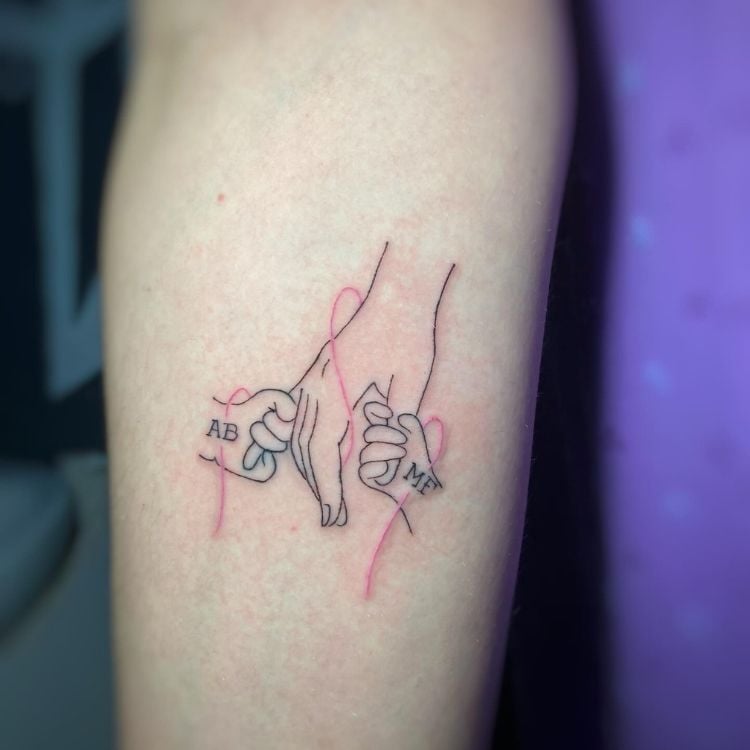 Tatuagem de mão grande abraçada por duas mãos pequenas com iniciais "ab"e "mf"