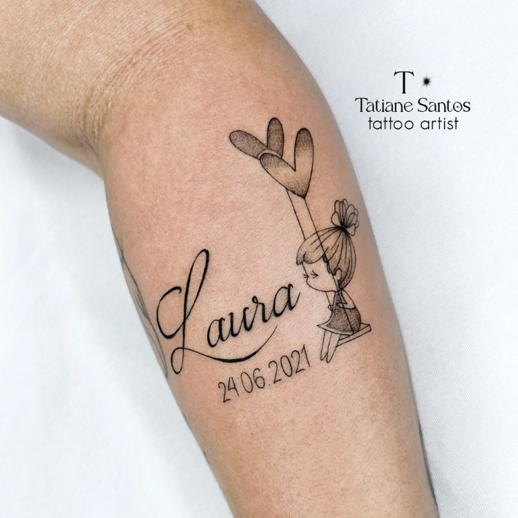 Braço de pessoa de pele clara com tatuagem escrito "Laura", desenho de menina em balanço com corações e data de nascimento