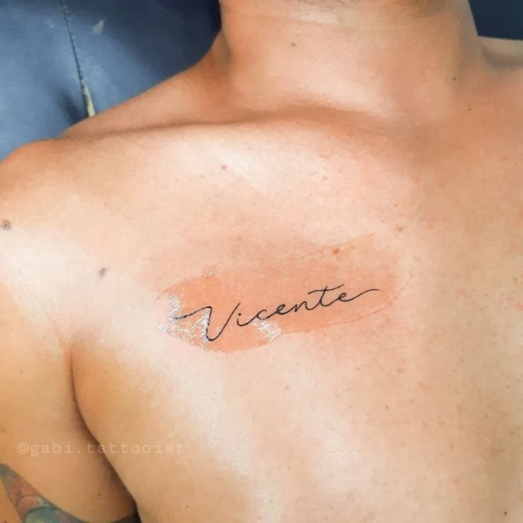 Ombro de homem de pele clara com tatuagem escrito "Vicente"