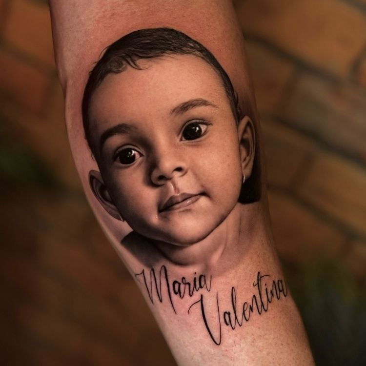 Tatuagem realista de retrato de uma bebê com nome "Maria Valentina"