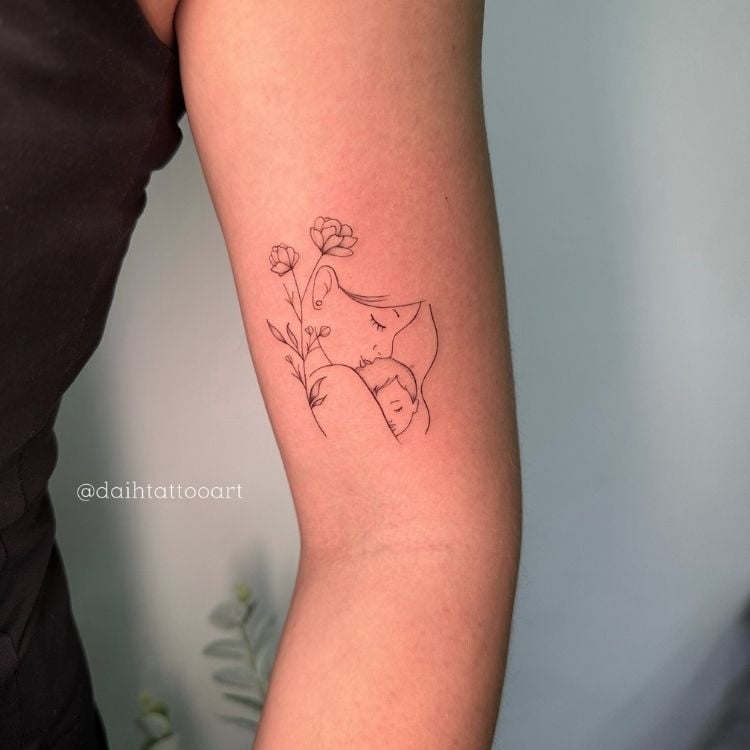 Braço de mulher de pele clara com tatuagem de contorno de desenho de mãe e filha com flores
