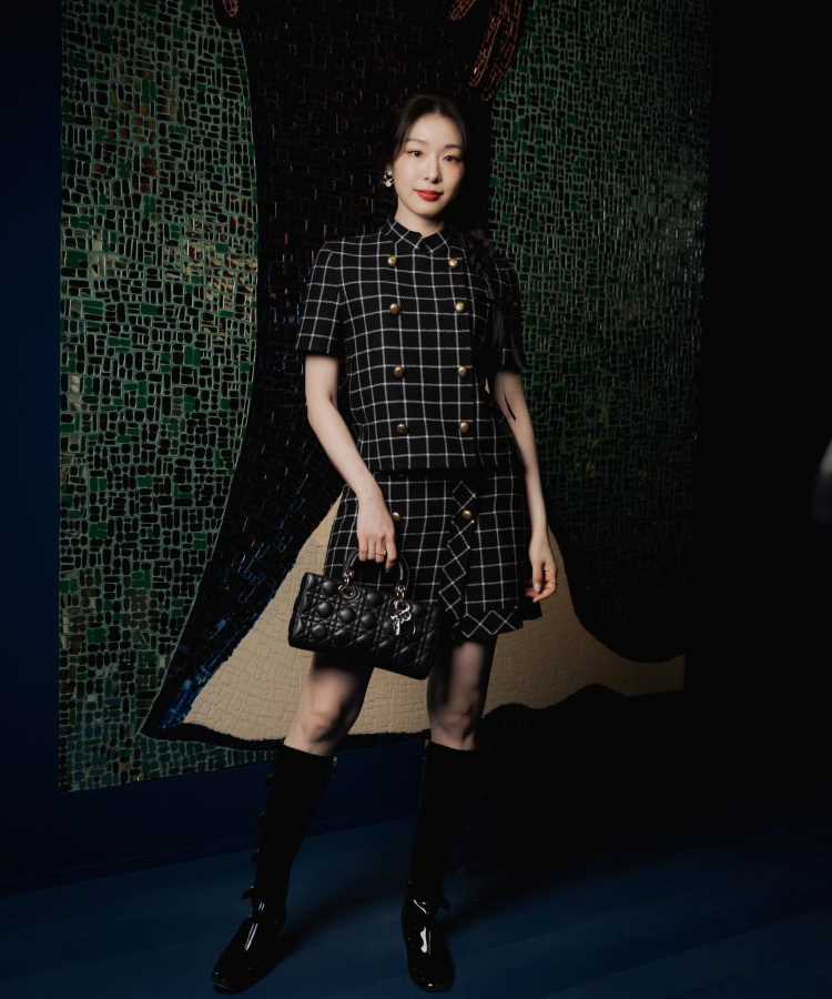 Mulher japonesa usando Vestido xadrez preto de mangas curtas, saia combinando, botas pretas e bolsa acolchoada. Look moderno e elegante.