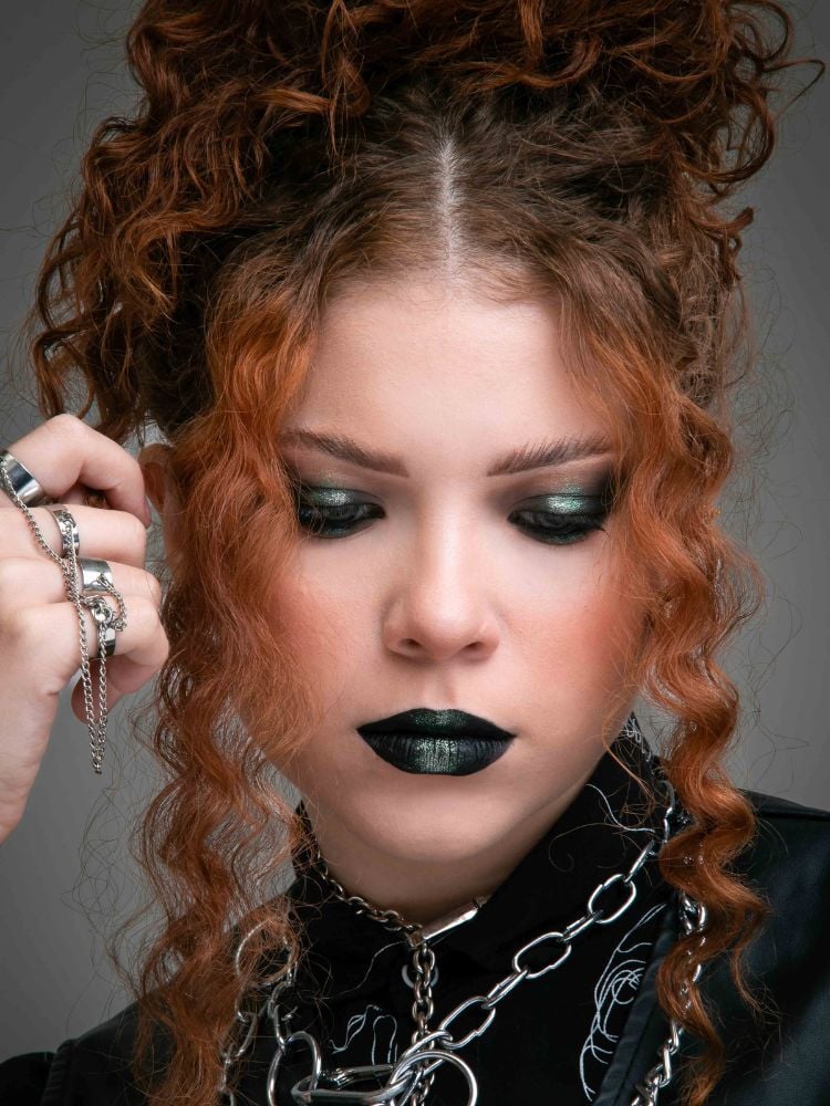 Mulher ruiva usando maquiagem para o Dia do Rock: smokey eyes e batom preto