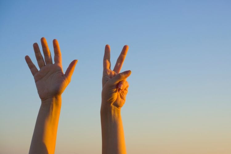 Foto de céu azul com mãos de pessoa levantando 7 dedos