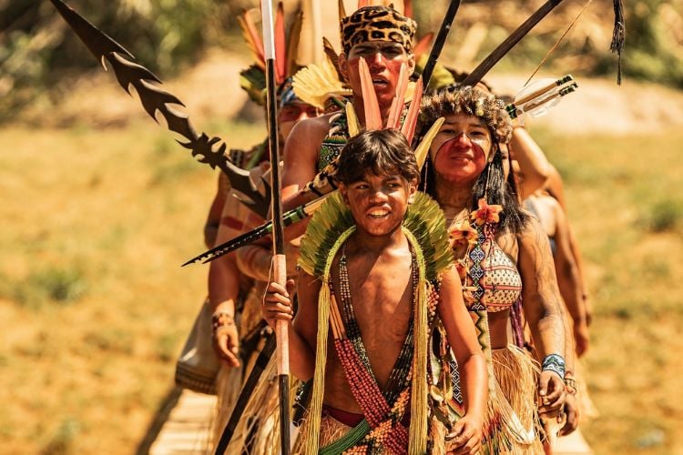 Foto de indígenas pintados atravessando a Ponte do Mariri Yawanawa