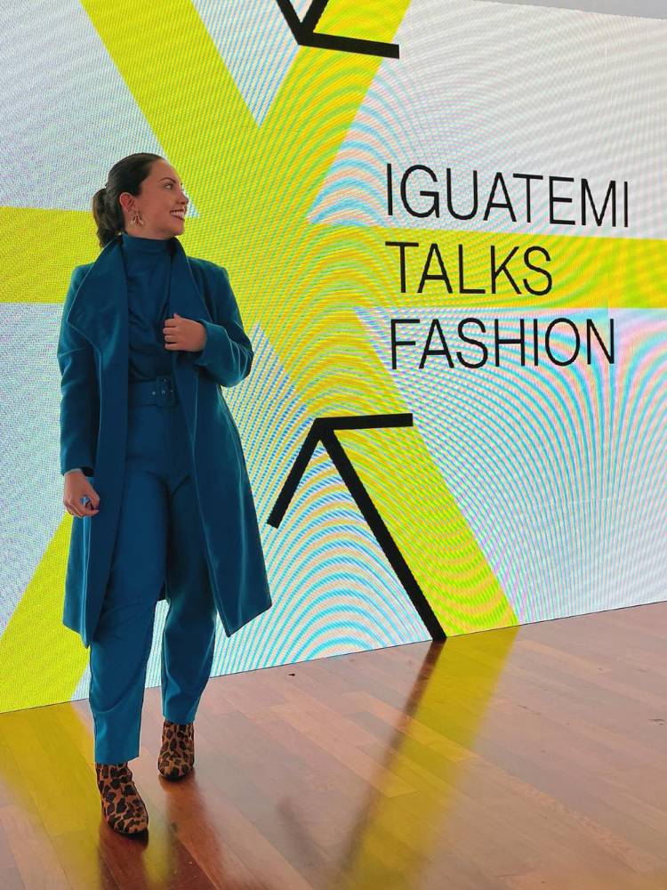 Thaís Galvão de look azul com telão do Iguatemi Talks Fashion atrás