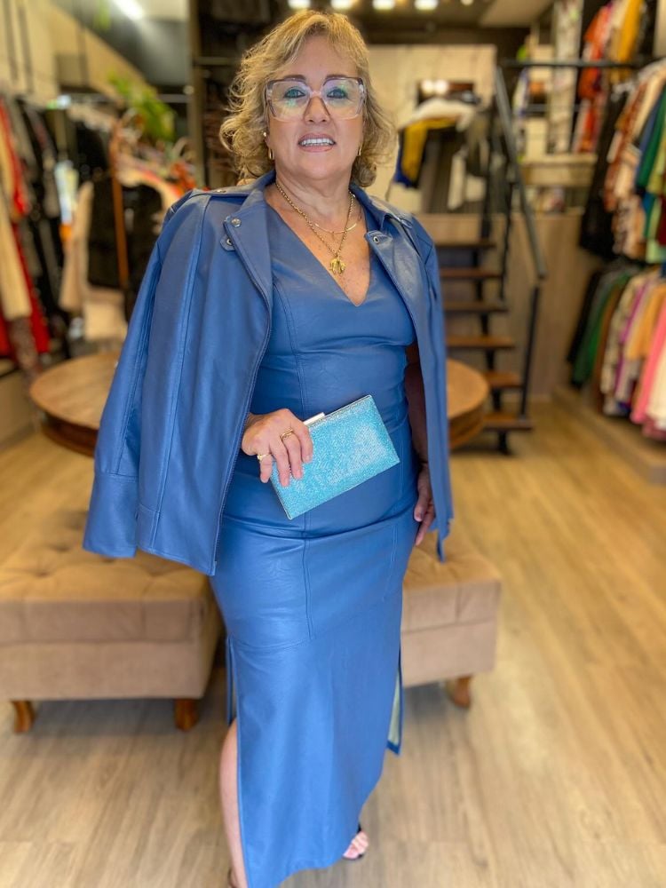 Mulher idosa de pele clara usando vestido midi de couro azul, jaqueta de couro de mesmo tom e bolsa azul clara