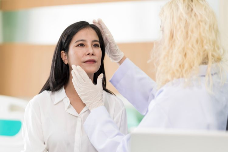 Médica analisando o rosto de uma mulher que deseja fazer procedimentos estéticos. 